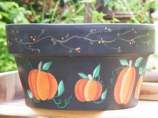 Black flower pot with pumpkins on it.